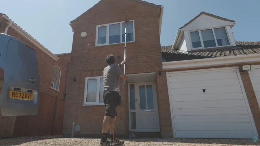 Technician using an extension pole to clean a second-story exterior window