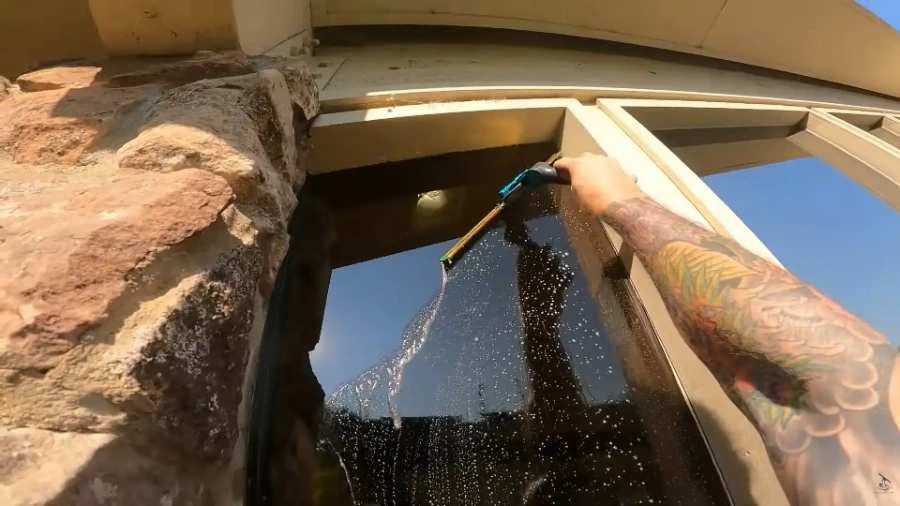 Close-up of a squeegee cleaning soapy water from an exterior window