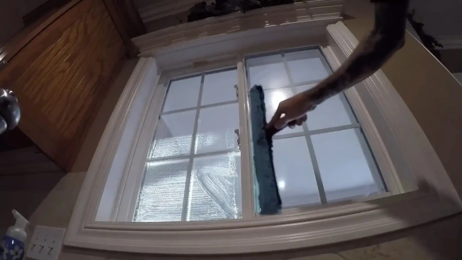 Technician washing the inside of a multi-pane window with a scrubber sleeve