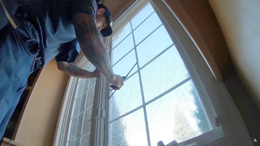 Technician cleaning the inside of an arched, multi-pane window