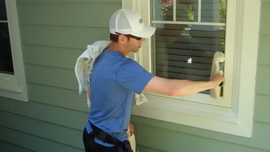 Window cleaner wiping the glass in a front door on a home's covered porch