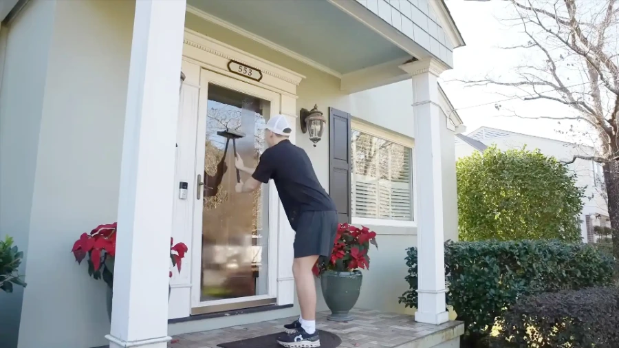 Residential window cleaning technician cleaning glass at the front entry of a San Clemente home