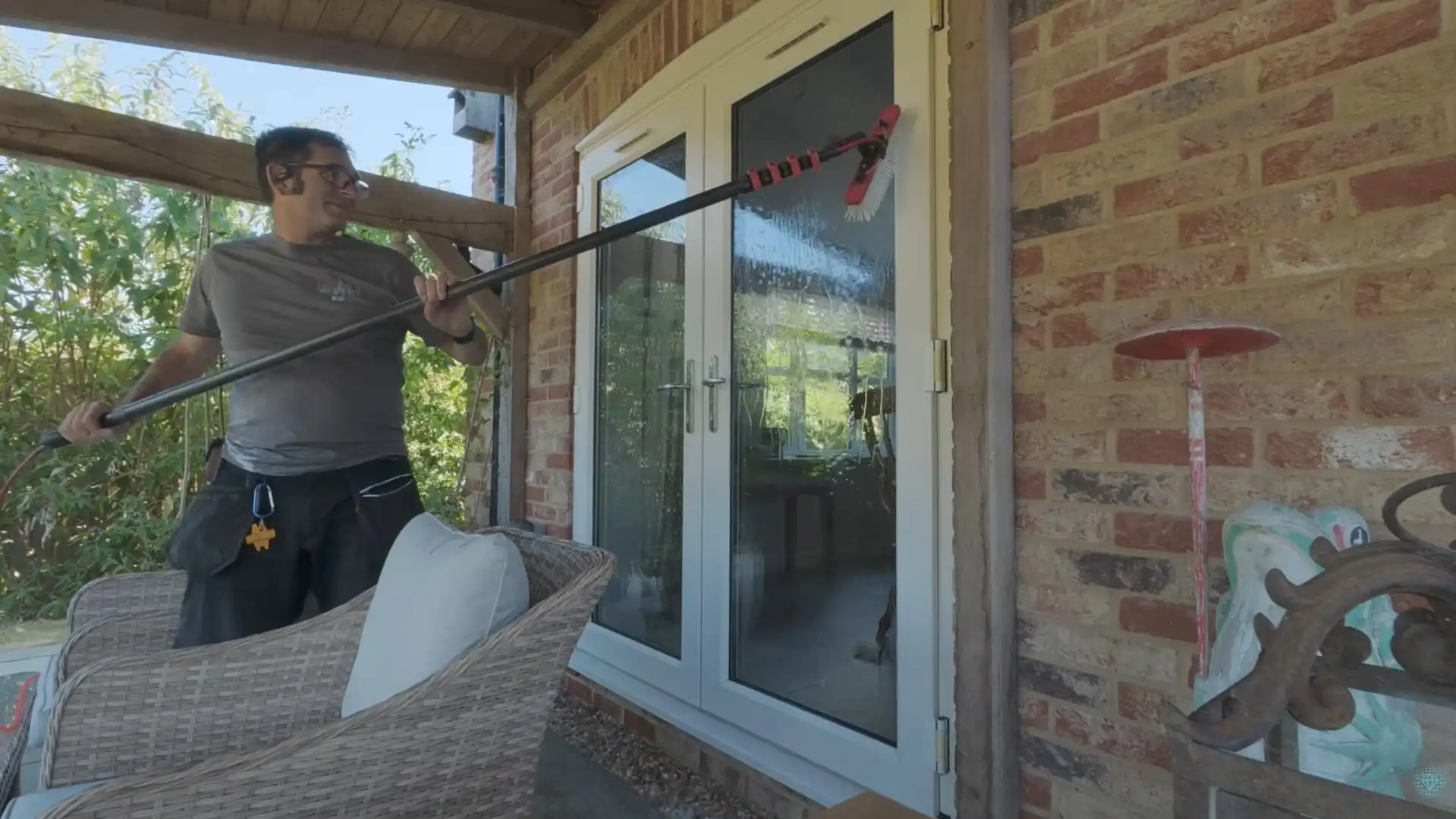 Technician using an extension pole to clean glass patio doors at a home